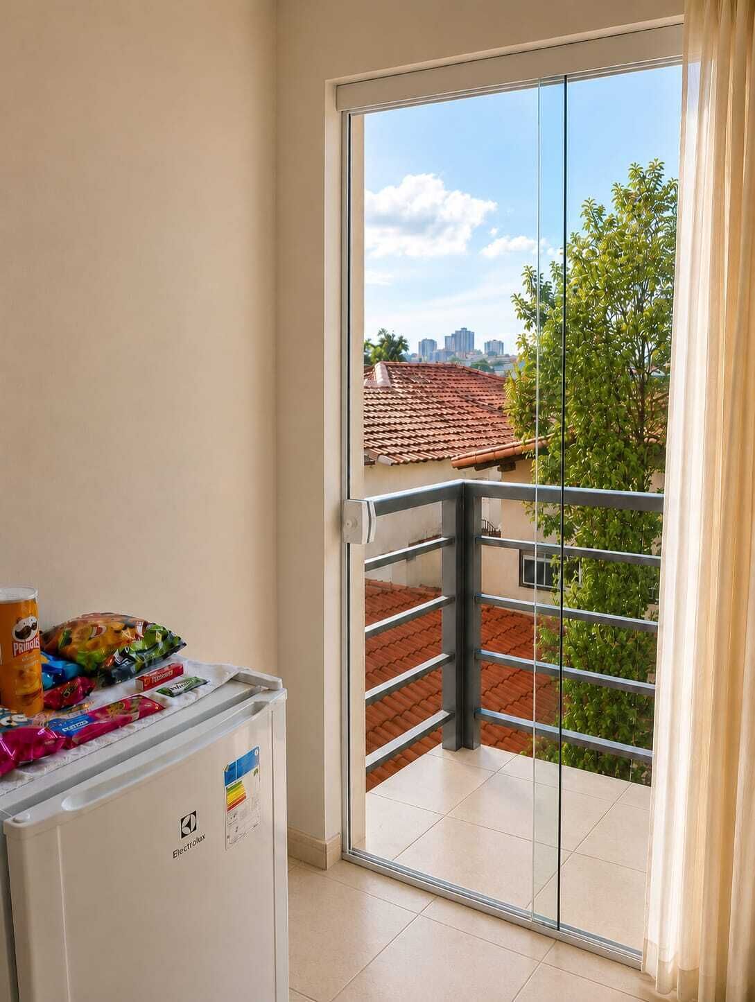 A balcony with a glass door, a small refrigerator, and a bag of snacks.