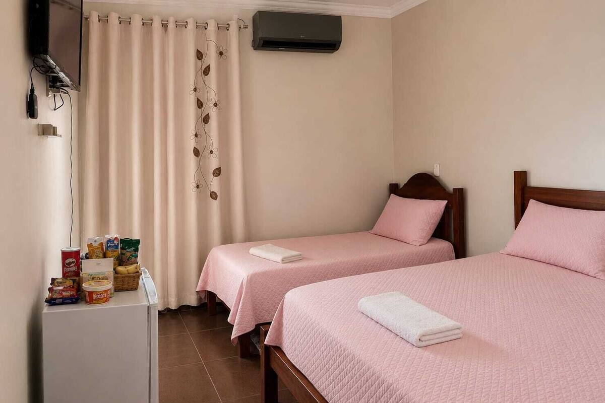 Une chambre avec deux lits, une télévision, un climatiseur et une petite table avec des collations.