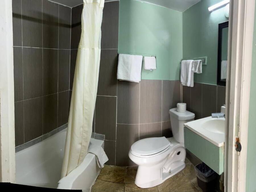 Un baño con ducha, inodoro, lavamanos y espejo.