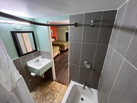 A bathroom with a bathtub, a sink, and a mirror.