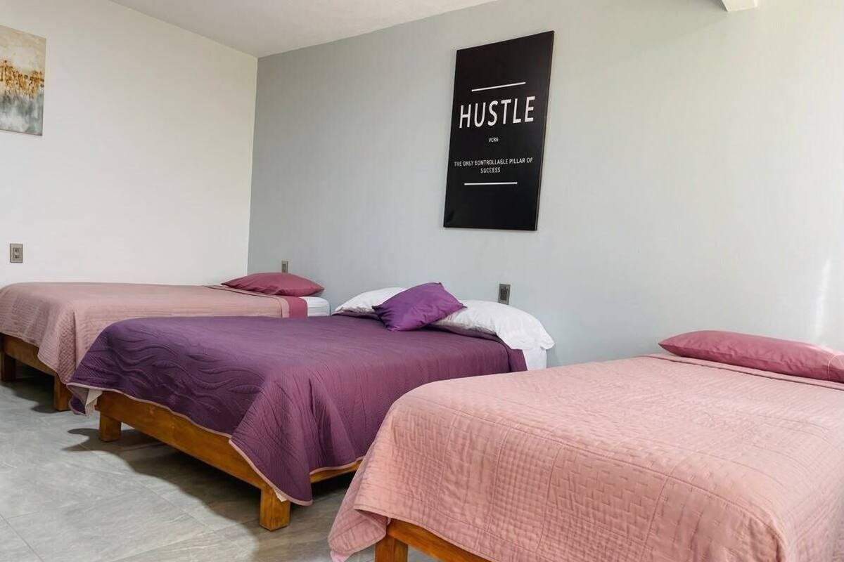 Una habitación con tres camas, cada una con una colcha de diferente color.