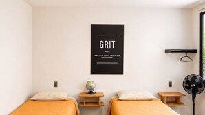 Una habitación con dos camas, un globo terráqueo, un ventilador y un cartel motivacional.