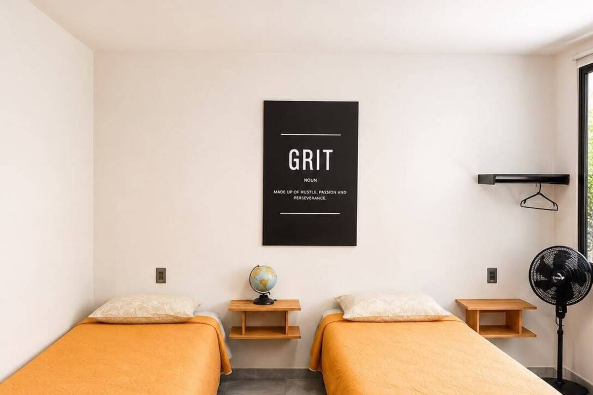 Una habitación con dos camas, un globo terráqueo, un ventilador y un cartel motivacional.