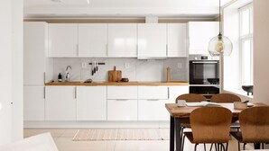 Una cocina moderna con armarios blancos, encimera de madera y comedor con mesa y sillas.