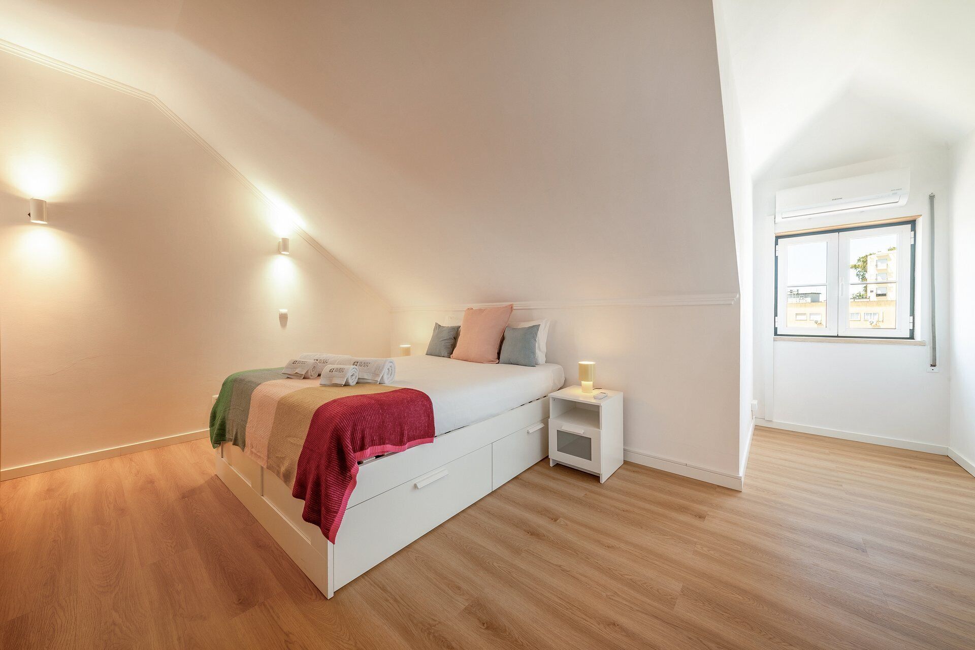 Une chambre à coucher avec un lit, une table de chevet et une fenêtre.