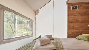 Ein Zimmer mit einem Bett, einem Fenster und einer Holzwand.