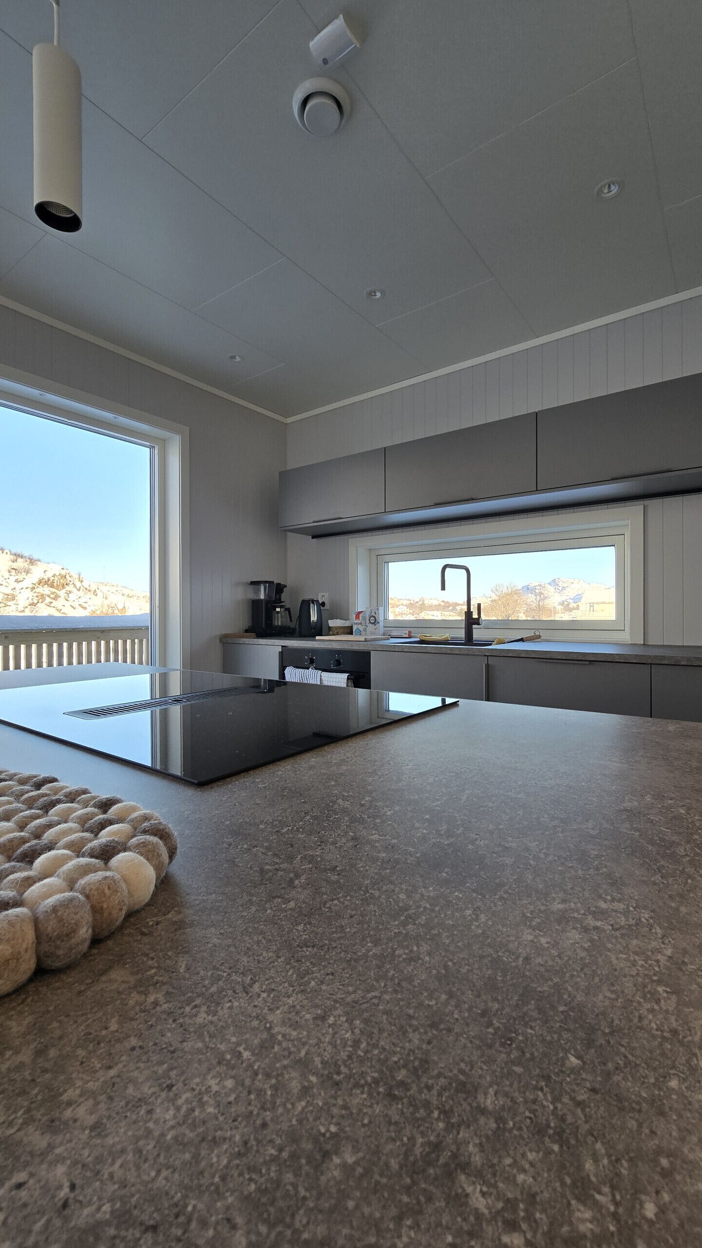 A modern kitchen with a large island, a window with a view, and a ceiling-mounted camera.