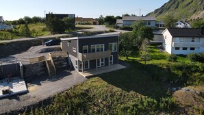 Un edificio moderno con tetto piatto, ampie finestre e una piccola terrazza.