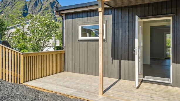 Un pontile in legno con una porta che dà su una stanza, una finestra e vista sulle montagne.
