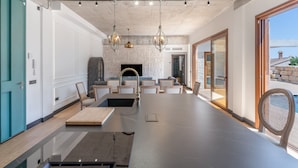 A modern kitchen with a large island, pendant lights, and a view to the outside.