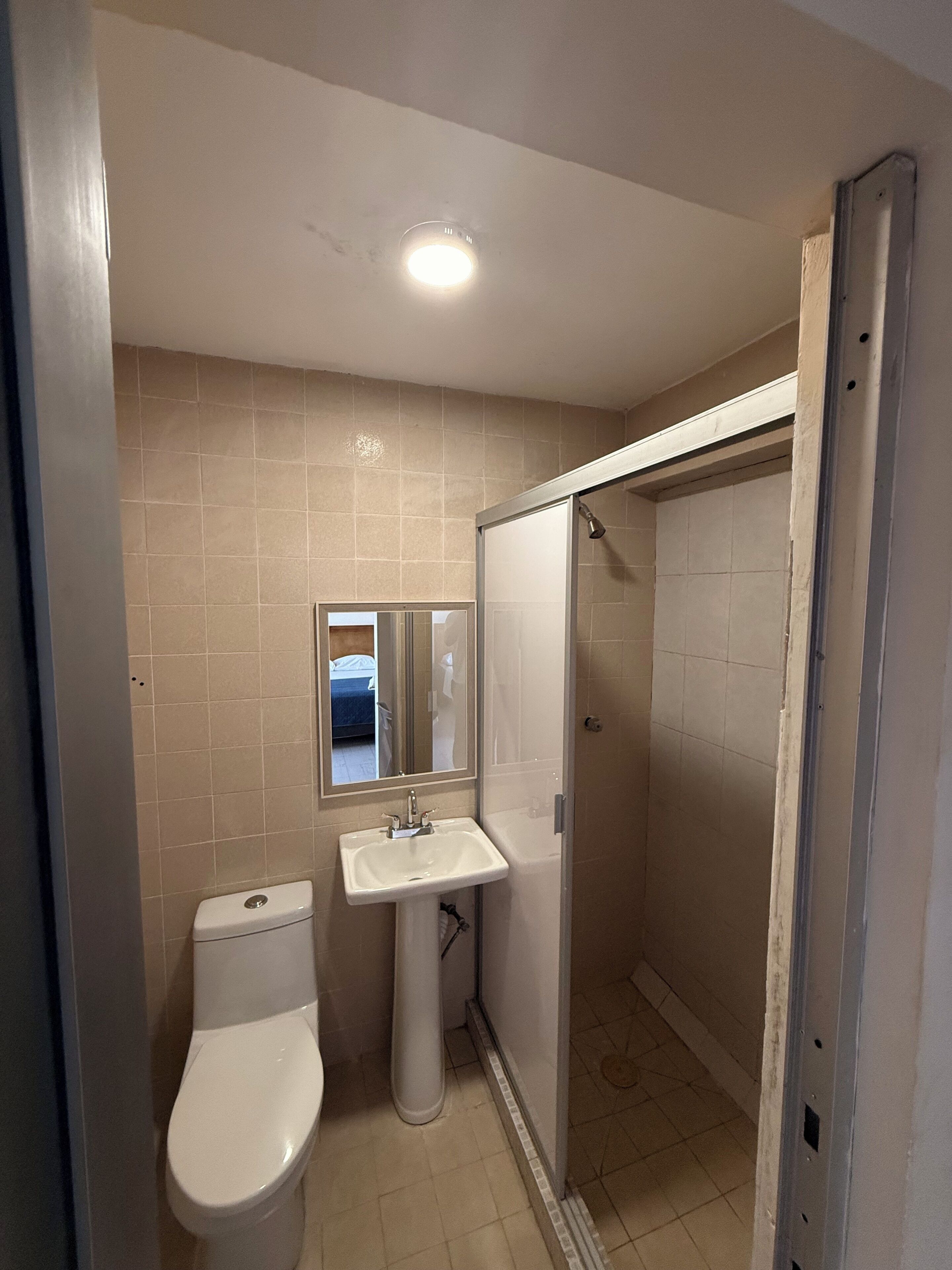 Eenvoudige tweepersoonskamer | Badkamer | Een douche, handdoeken, zeep, shampoo