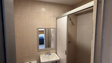 Eenvoudige tweepersoonskamer | Badkamer | Een douche, handdoeken, zeep, shampoo