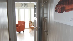 A hallway with a tiled floor, a door with a handle, and a framed picture on the wall.