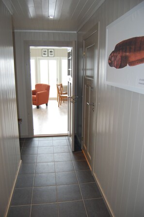 A hallway with a tiled floor, a door with a handle, and a framed picture on the wall. - Thor-Bua, Sund in Lofoten (Flakstad)