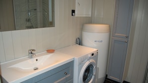 A bathroom with a sink, a washing machine, and a cabinet.