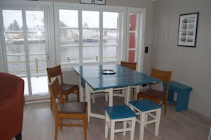 A dining area with a table and chairs, large windows with a view of a snowy outdoor scene, and a framed picture on the wall.