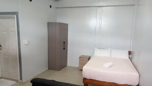 Un dormitori amb un llit, un armari, una commode i una banca de pell negra.