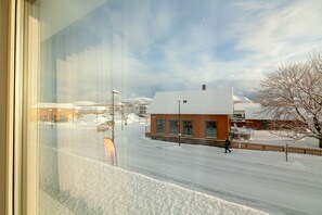 A snowy street with buildings, a clear sky, and a person walking.