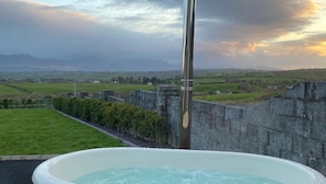 A hot tub with a view of a rural landscape and mountains in the background. - Studio Sleeps 2 -private Hot Tub -enclosed Garden (Killarney)