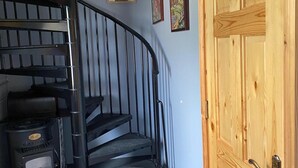 A spiral staircase with a black metal railing, a wooden door, and three framed artworks on the wall. - Studio Sleeps 2 -private Hot Tub -enclosed Garden (Killarney)