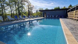 Una piscina con sillas de descanso y una zona techada.