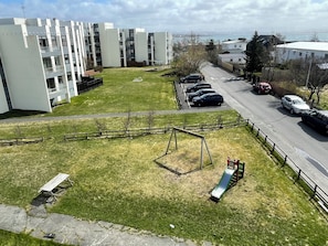 A residential area with a playground, parked cars, and a building with balconies.