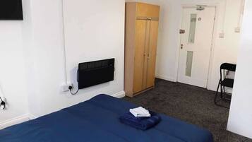 A room with a bed, a wardrobe, a door, and a chair.