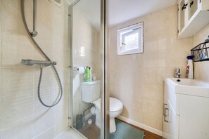 Ein Badezimmer mit Duschkabine aus Glas, Toilette und Waschbecken mit Schrank.