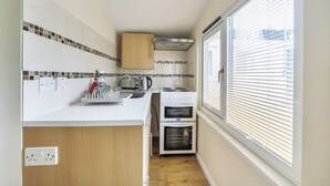 Eine kleine Küche mit Fenster, inklusive Herd, Backofen und Spüle.