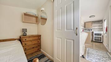 Um quarto com cômoda de madeira, luminária de cabeceira e uma cama.
