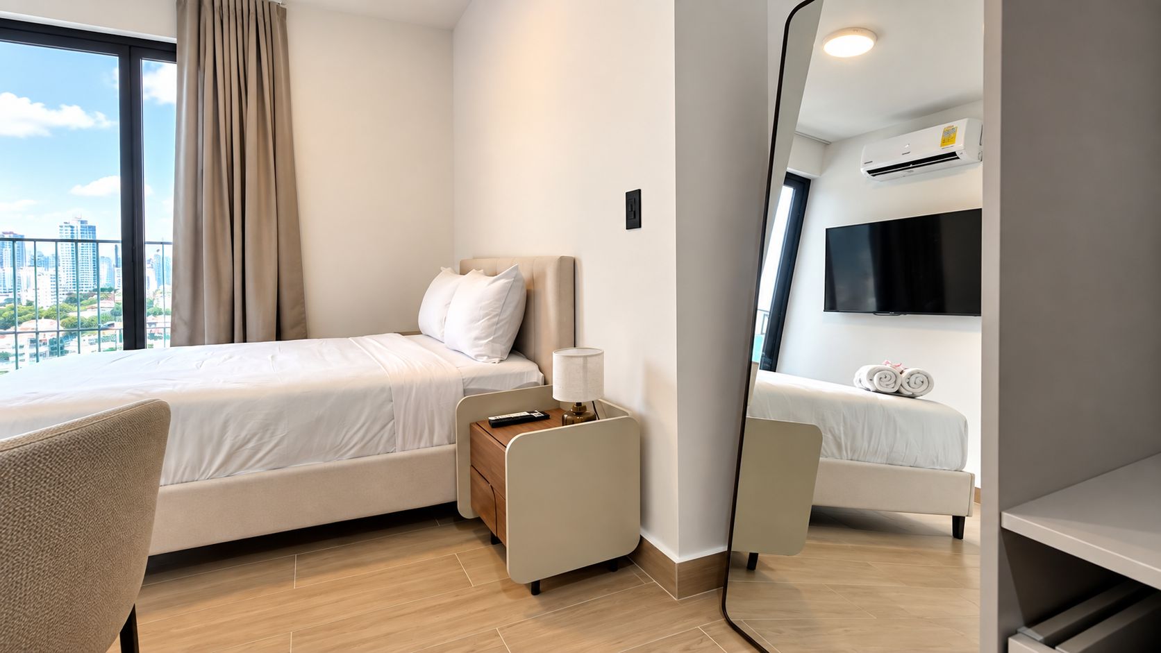 Habitación de hotel con cama, escritorio, silla, televisor y vista a la ciudad.