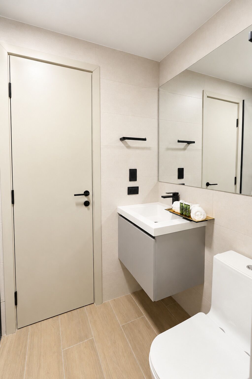 A modern bathroom with a white door, a sink with a mirror above it, and a toilet.