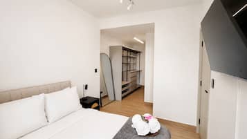 Un dormitorio moderno con cama, mesita de noche y un taburete con toallas.