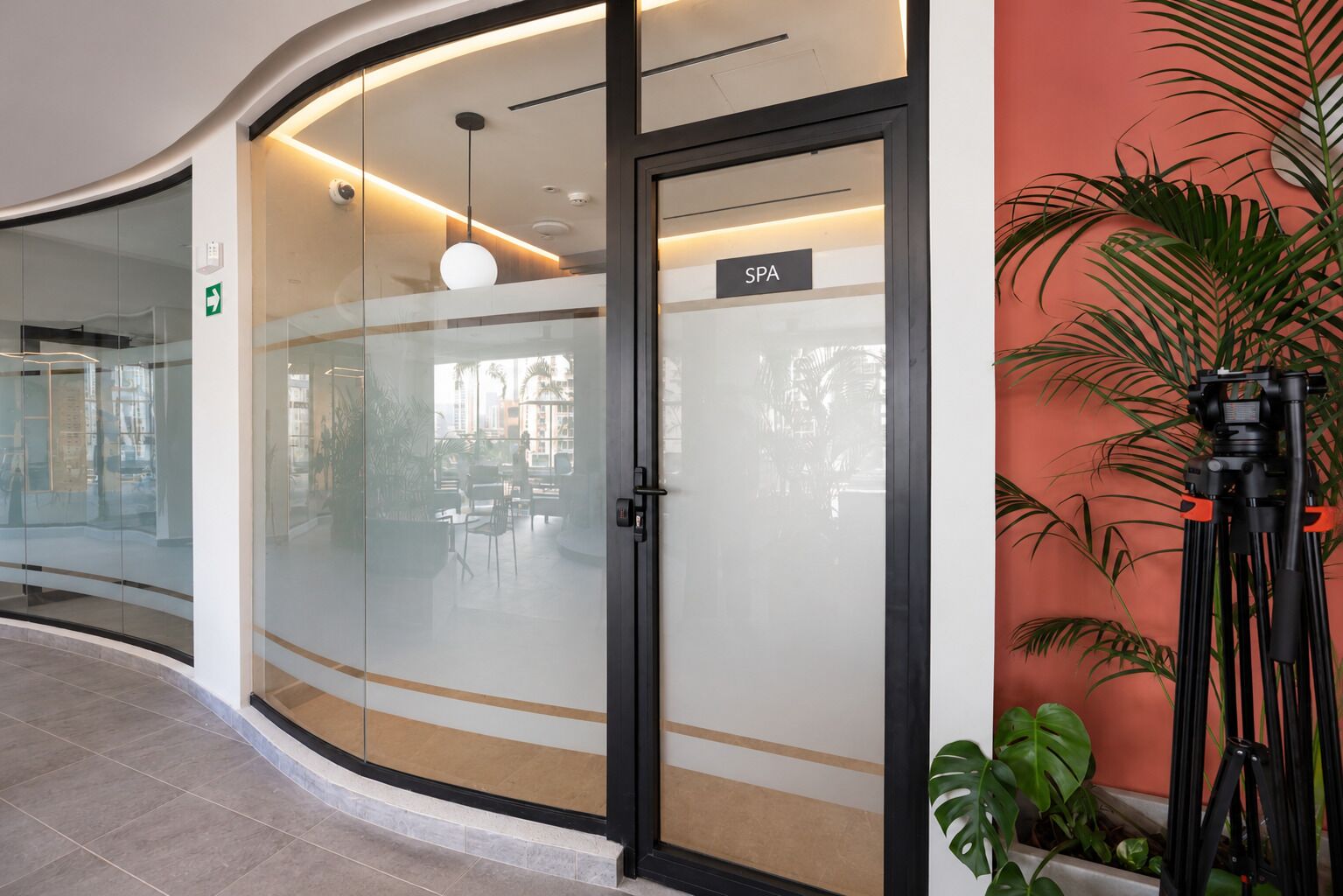 Un intérieur moderne avec une porte vitrée donnant sur un espace de bien-être, un luminaire au plafond et une plante en pot.
