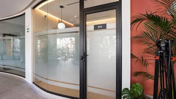 Un intérieur moderne avec une porte vitrée donnant sur un espace de bien-être, un luminaire au plafond et une plante en pot.