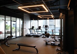 Ein Fitnessstudio mit Laufbändern, Kraftgeräten und einer Bank.
