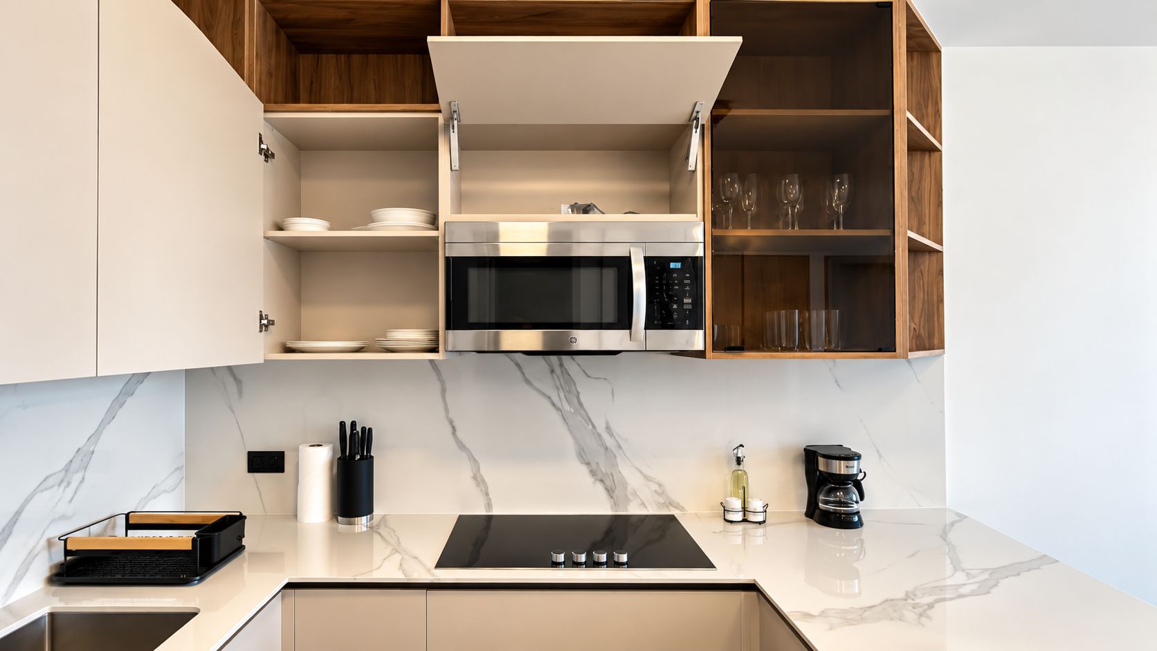 A modern kitchen with a built-in microwave, a coffee maker, and a sink.