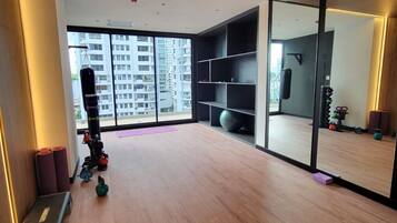 A modern gym with wooden flooring, exercise equipment, and a large window offering a city view.