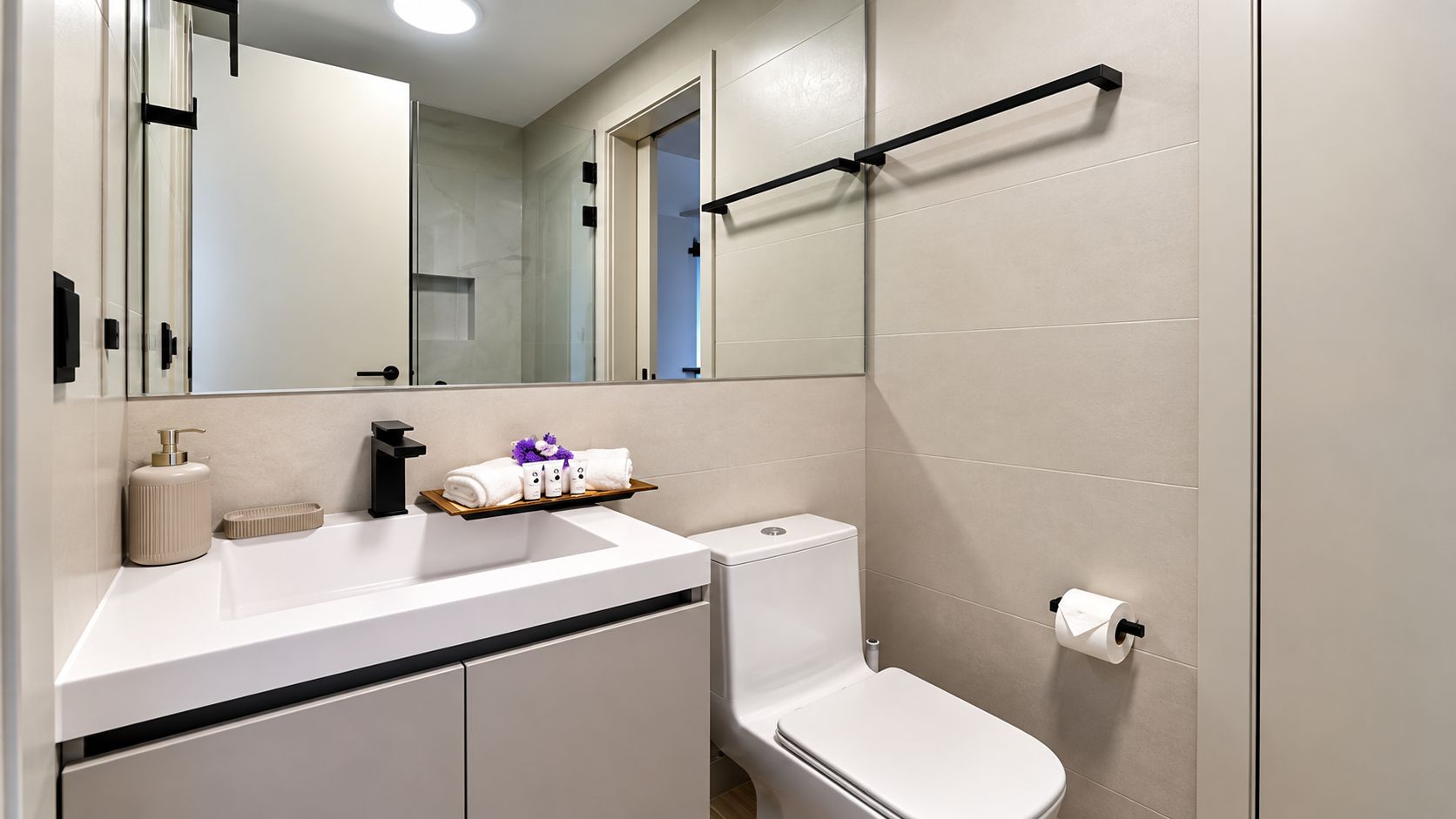 A modern bathroom with a white sink, a toilet, and a glass shower enclosure.