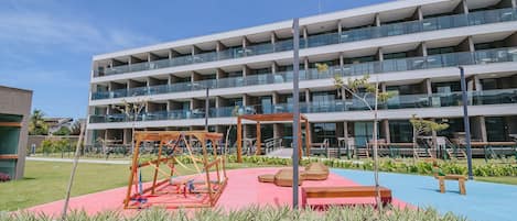 A multi-story building with a rooftop terrace and a playground area with swings and seating.