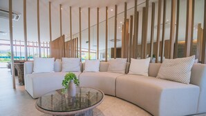 Uma sala de estar moderna com um sofá seccional, uma mesa de centro de vidro e uma planta decorativa.