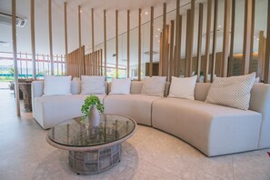 Ein modernes Wohnzimmer mit einem Ecksofa, einem Glastisch und einer Zierpflanze.