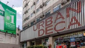 Ein Gebäude mit einer großen Schrifttafel mit dem Schriftzug 'URBAN BEA' und einer grünen Werbetafel, die 'Absolute #1 Destilliertes Wasser Philippinen' bewirbt.