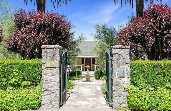 A stone entrance gate, a stone pathway, and a building with a porch.