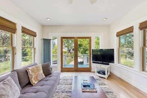 A living room with a sofa, a coffee table, a TV, and large windows.