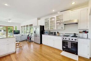 A spacious kitchen with white cabinetry, a large stove, and a dining area with a sofa.