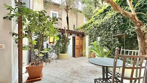A courtyard with a table and chairs, potted plants, and a wooden door. - Charming Suite in the Heart of Cannero Riviera, Lake Maggiore (Cannero Riviera)