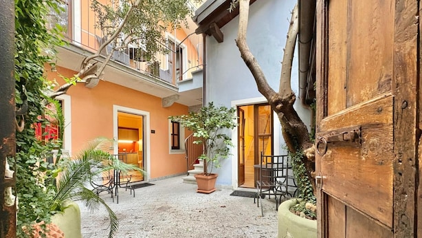 A courtyard with a wooden door, potted plants, and a tiled floor. - Charming Suite in the Heart of Cannero Riviera, Lake Maggiore (Cannero Riviera)