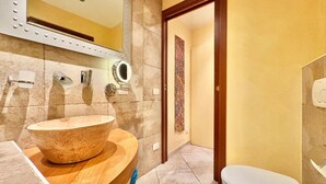 A bathroom with a large vessel sink, a mirror, a toilet, and a door leading to another room. - Charming Suite in the Heart of Cannero Riviera, Lake Maggiore (Cannero Riviera)