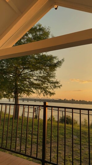Un espacio al aire libre techado con vista a un río y un puente distante.